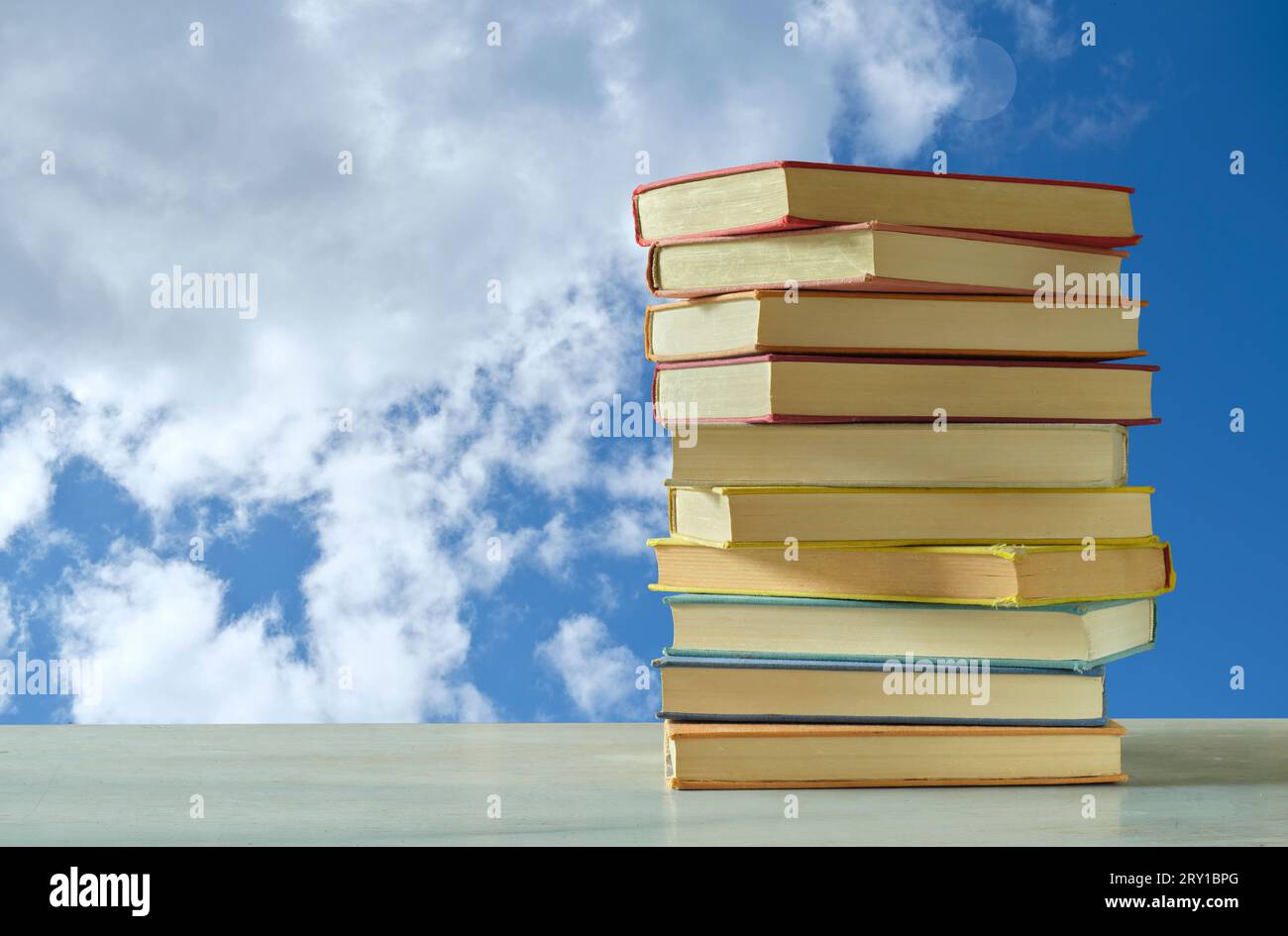 Pila di libri con sfondo blu cielo e nuvole, ispirazione, immaginazione, fantasia, letteratura, lettura, concetto di apprendimento Foto Stock