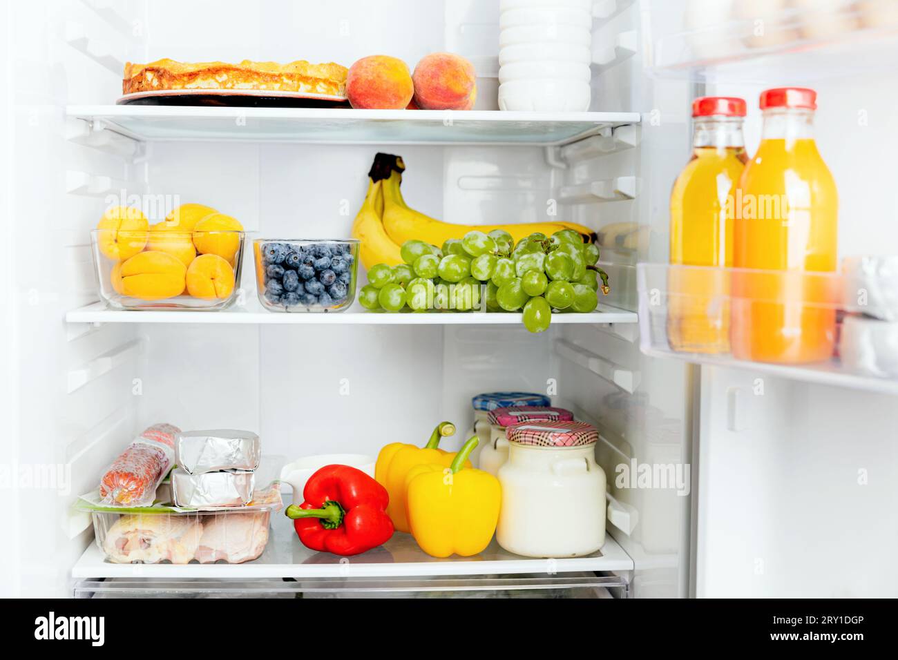 Vista frontale del frigorifero a due porte aperto o della porta del frigorifero riempito con frutta fresca, verdura, succo di frutta, pieno di cibi sani e ingredienti all'interno Foto Stock