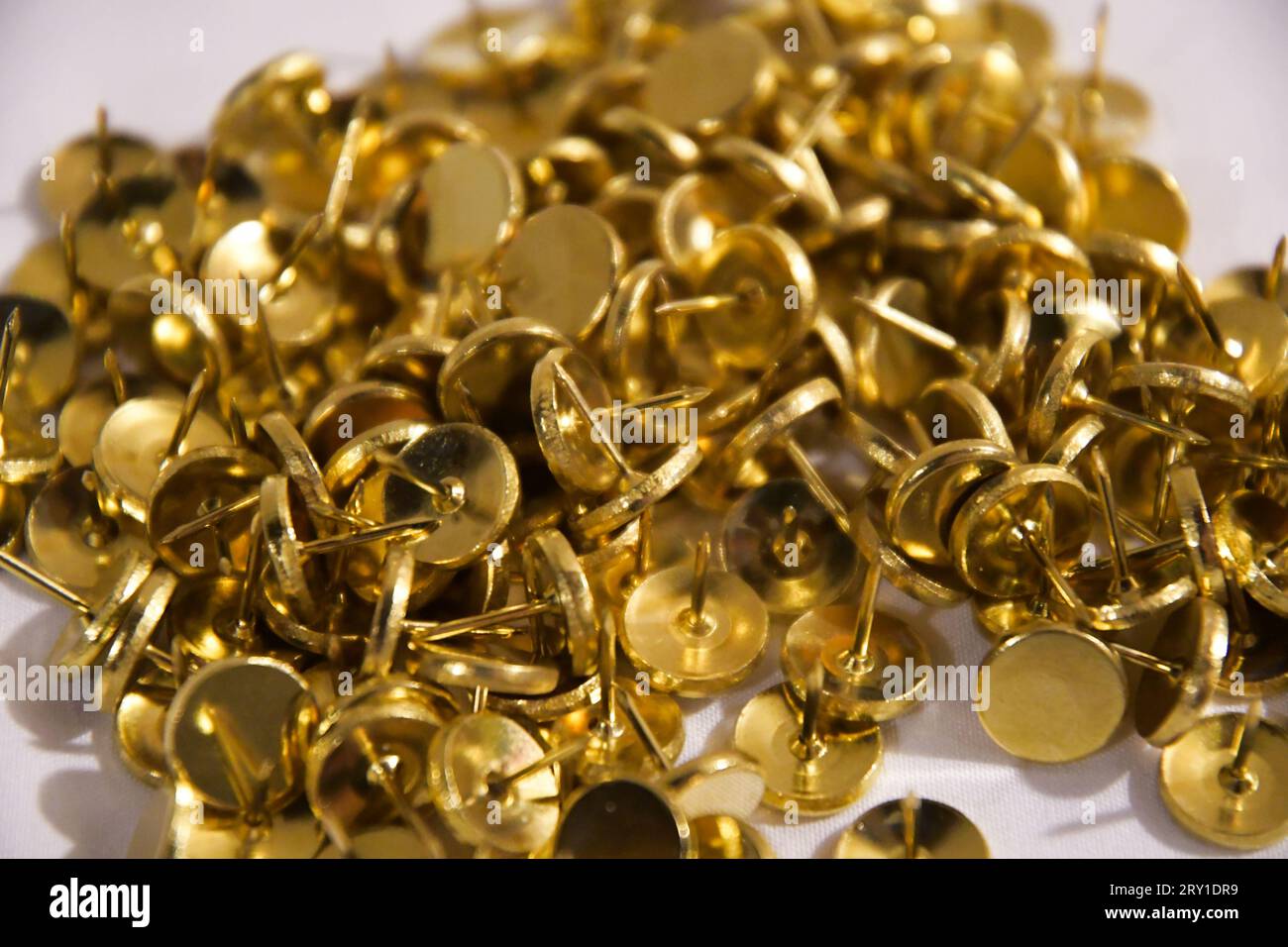 Una pila di spille a pressione tonalità oro a testa tonda in metallo lucido. Foto Stock