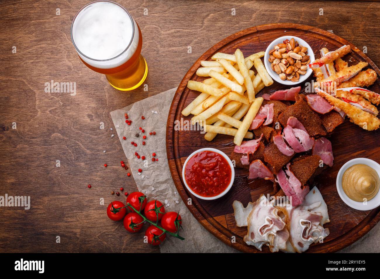 Ampia scelta di spuntini per birra o alcol e include carne di maiale affumicata, patatine fritte, pane fritto, bastoncini di granchio e noci servite con salse su legno Foto Stock