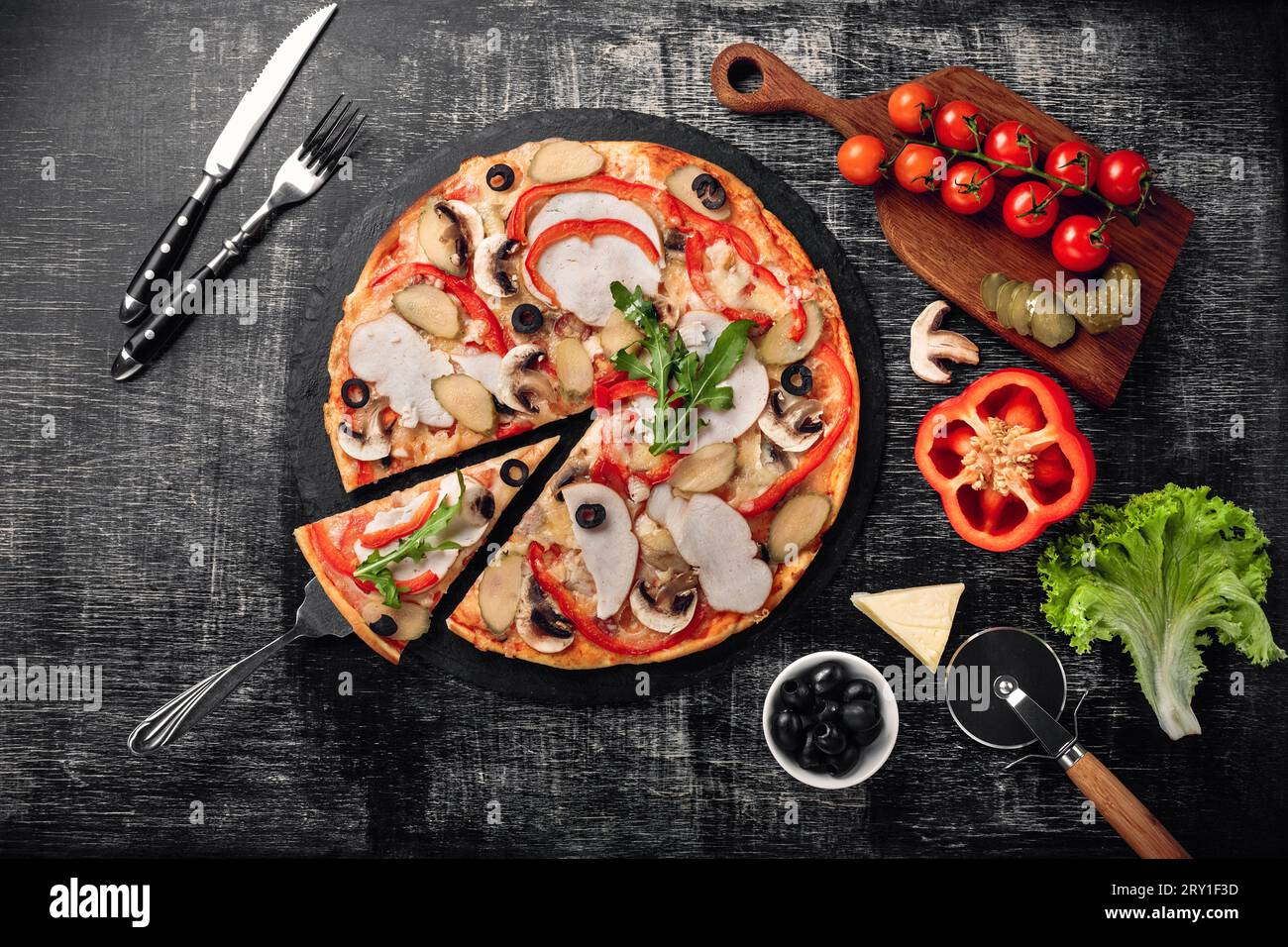 Pizza con formaggio, prosciutto, cetrioli sottaceto, carne e olive su una pietra e un lavagna di gesso nero, vista dall'alto. Foto Stock