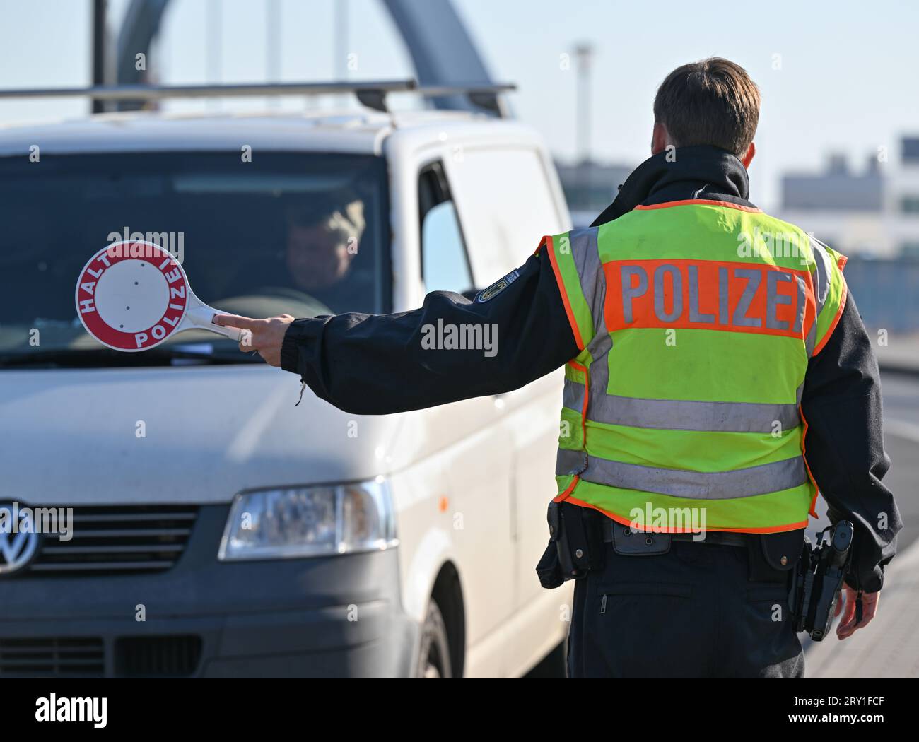 28 settembre 2023, Brandeburgo, Francoforte (Oder): Un ufficiale della polizia federale ferma il conducente di un furgone che entra nel paese al valico di frontiera tedesco-polacco di Stadtbrücke durante un controllo anti-contrabbando. Attualmente, i migranti vengono arrestati più volte al giorno in questa regione di confine con la Polonia. Foto: Patrick Pleul/dpa Foto Stock
