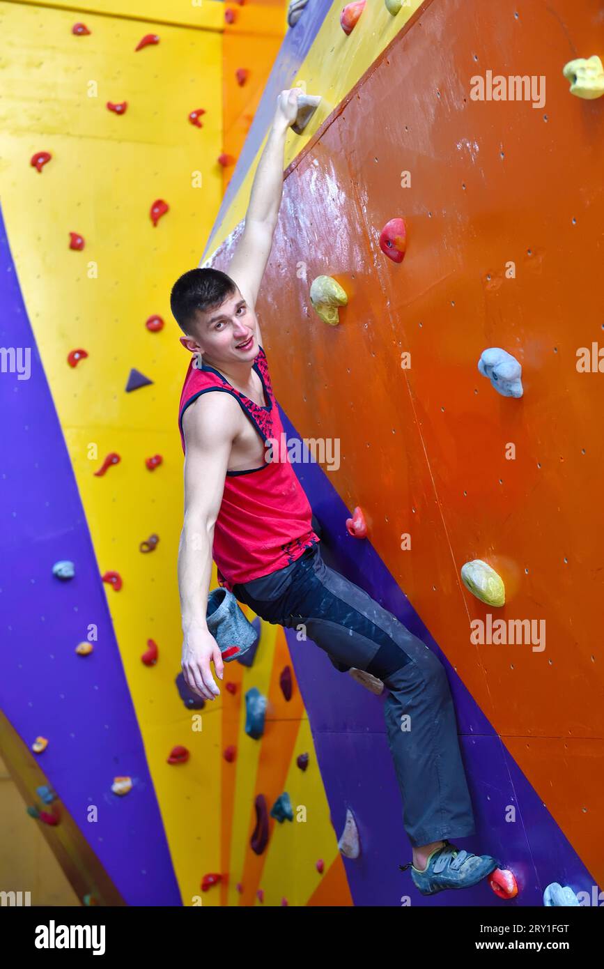 Arrampicata libera uomo su Color Practice Wall interni Foto Stock