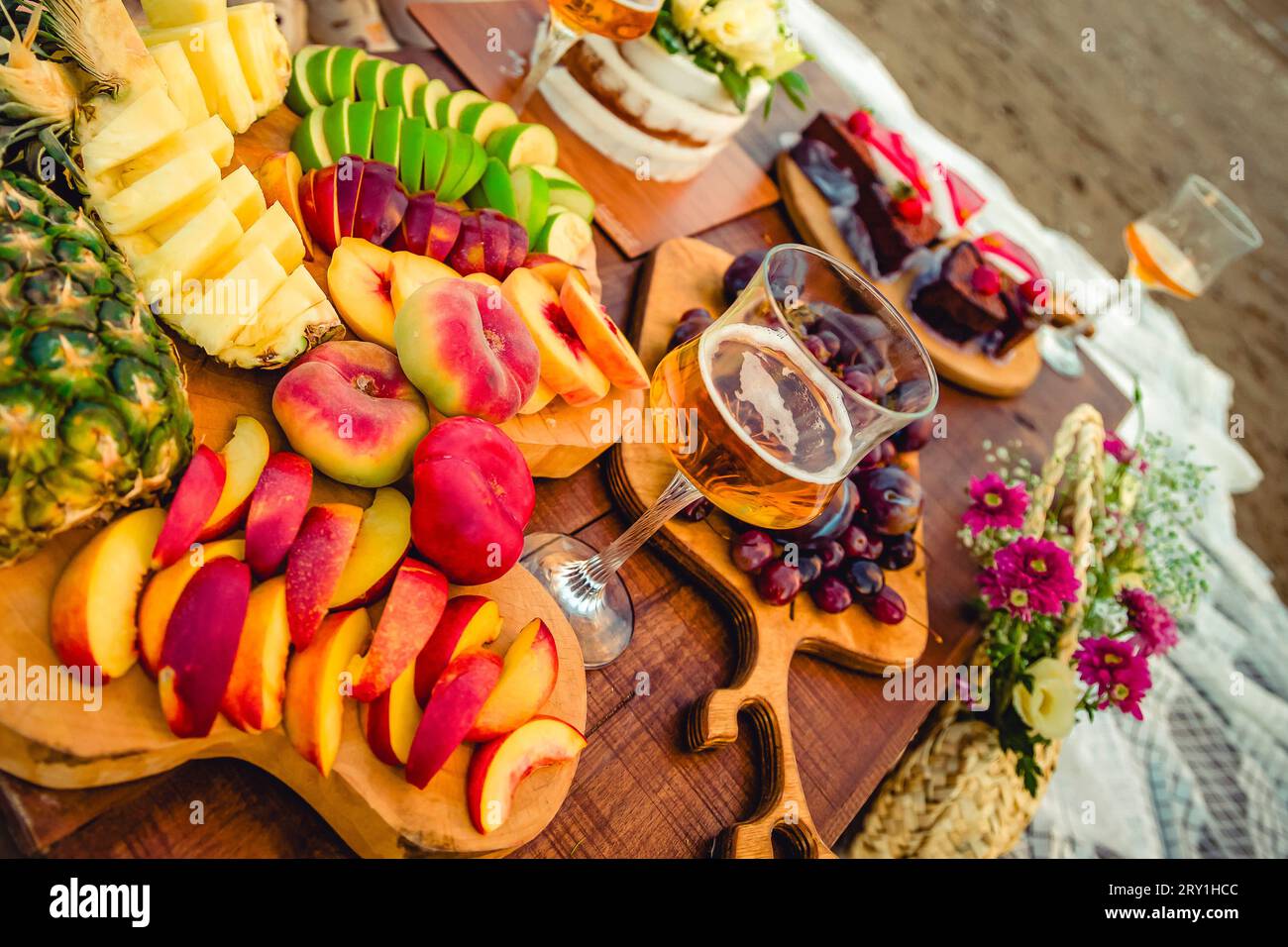 Un tavolo pieno di frutta a fette e torte sulla spiaggia. Foto Stock