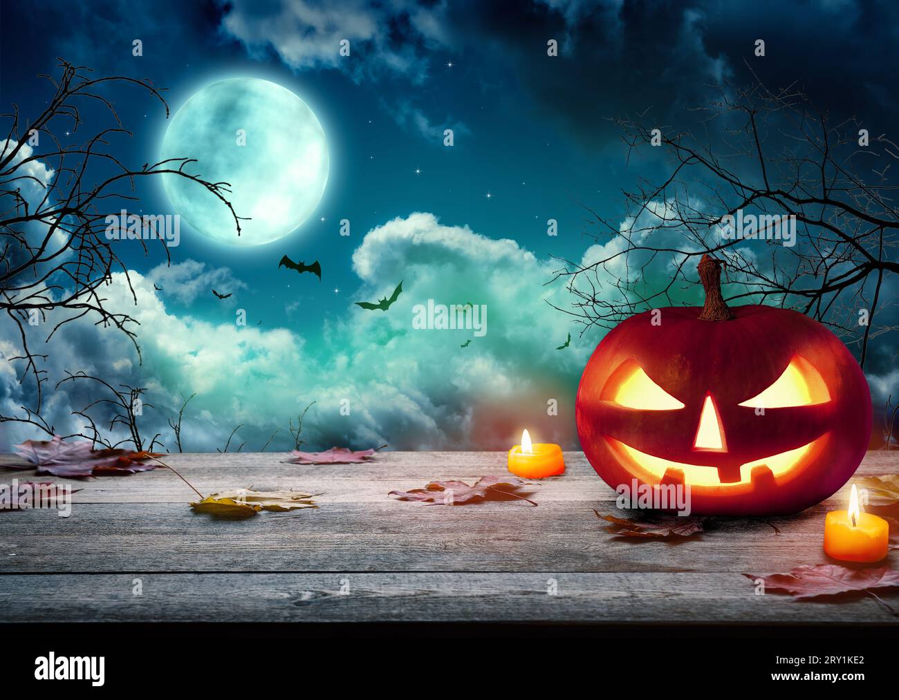 Le spaventose zucche di Halloween, Jack o Lantern, con un volto malvagio e occhi su un tavolo di legno con uno sfondo nebbioso e luna piena. Halloween Pumpkin con Foto Stock