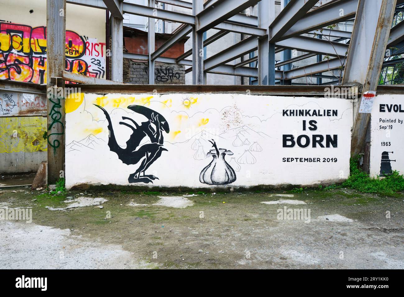 Un murale del mostro dei film di Alien, che guarda il famoso piatto georgiano, il khinkali, che dà alla luce un altro alieno. Uno dei tanti publi Foto Stock