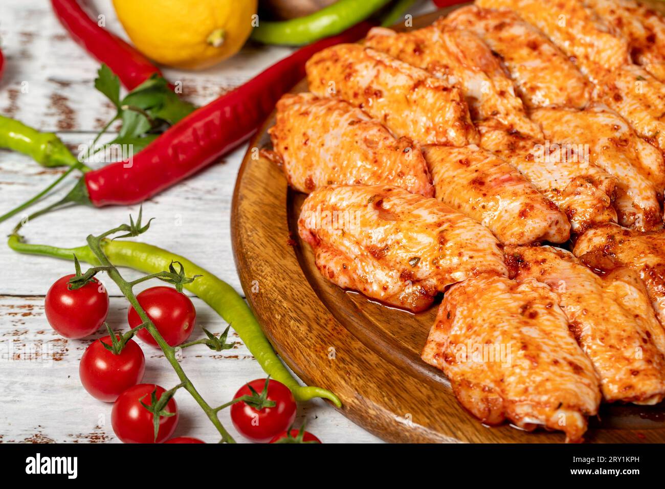 Ali di pollo con salsa su fondo di legno. Ali di pollo crude con erbe e spezie Foto Stock