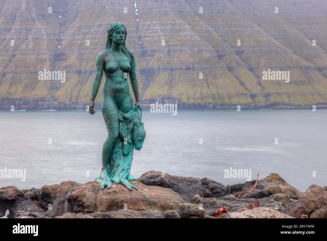 Il villaggio di Mikladalur sull'isola di Kalsoy con la sua statua della donna delle foche, le Isole Faroe. Foto Stock