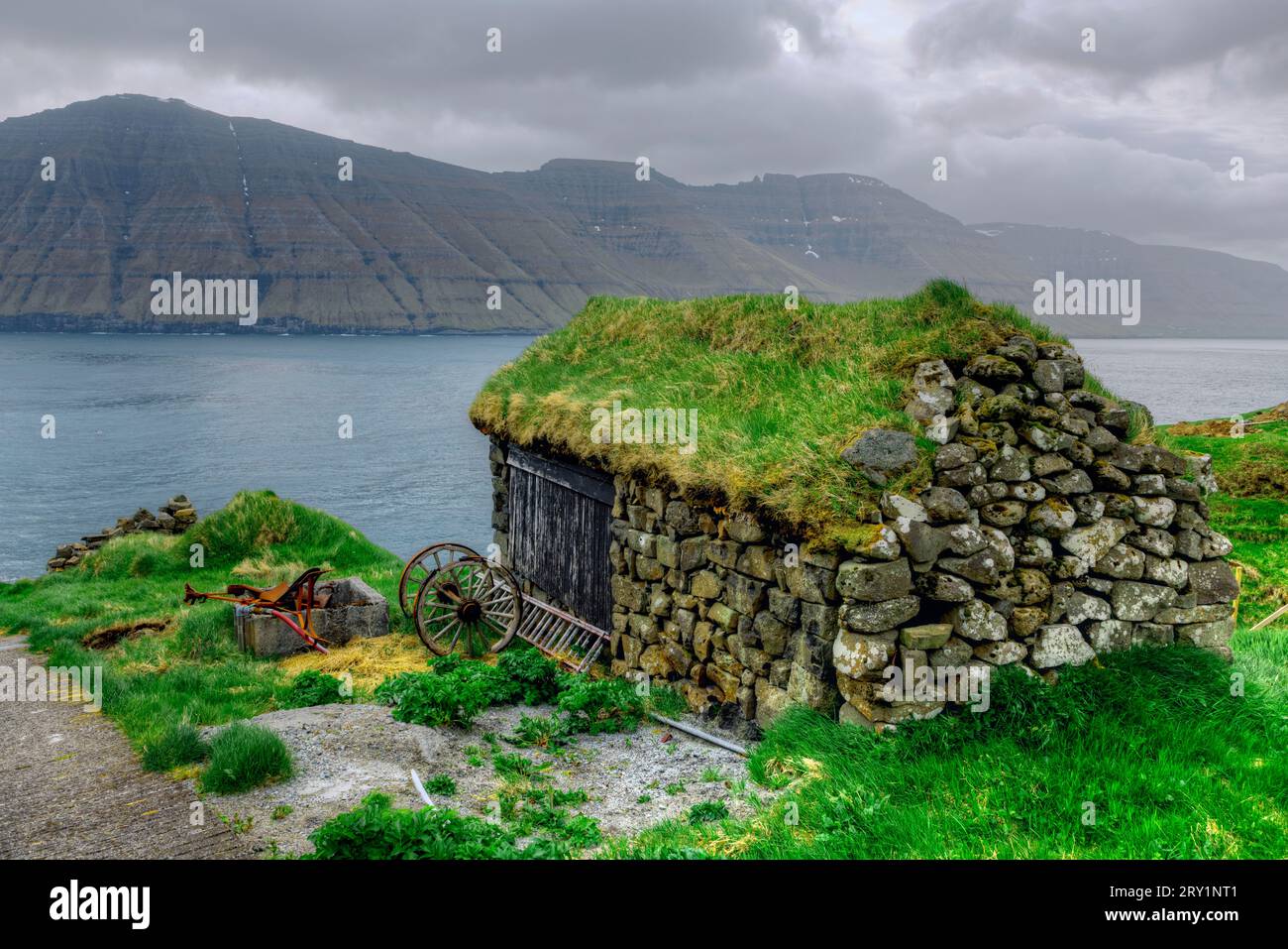 Il villaggio di Mikladalur sull'isola di Kalsoy con la sua statua della donna delle foche, le Isole Faroe. Foto Stock