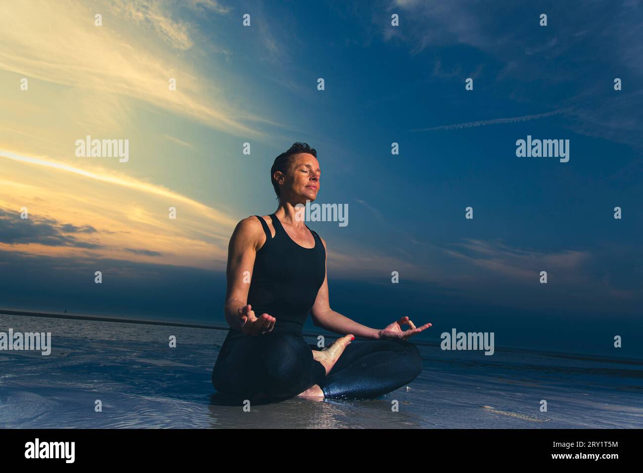 Donna sportiva che fa yoga in riva al mare Foto Stock