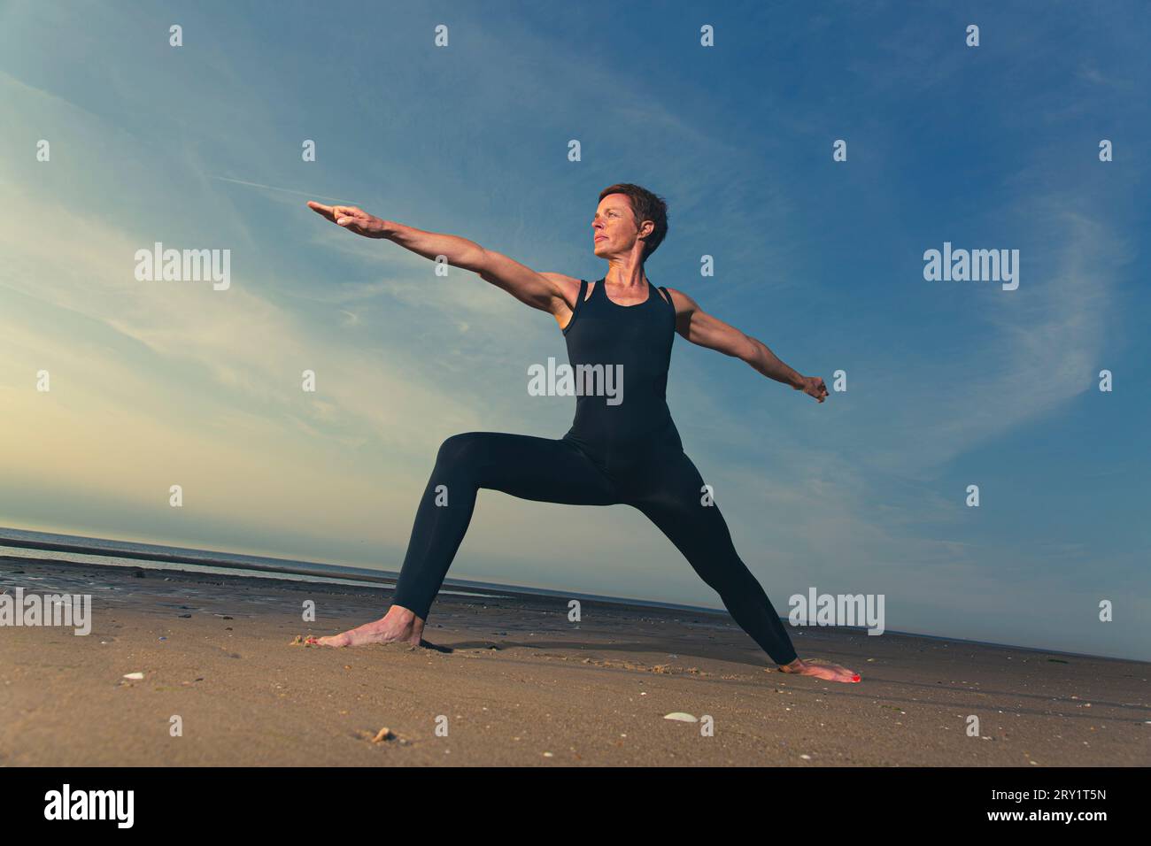 Donna sportiva che fa yoga in riva al mare Foto Stock