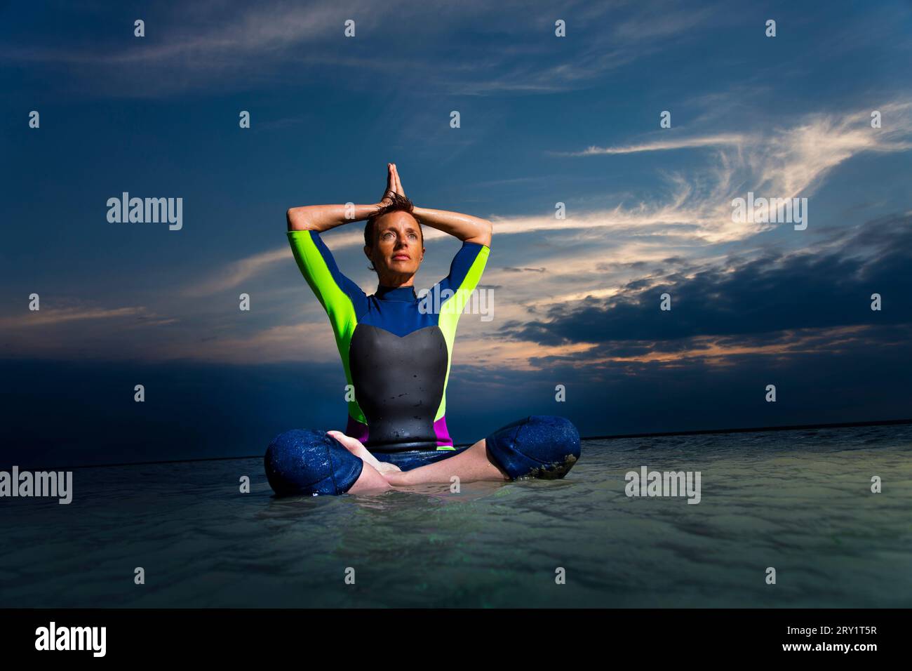 Donna sportiva che fa yoga in riva al mare Foto Stock