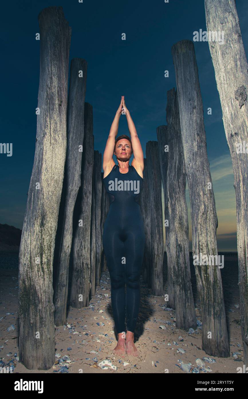 Donna sportiva che fa yoga in riva al mare Foto Stock