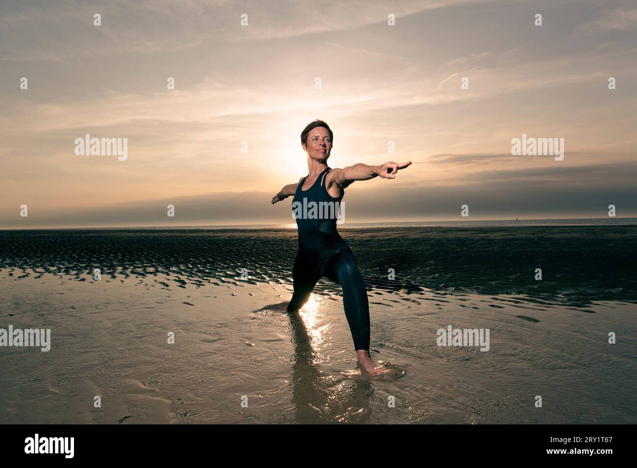 Donna sportiva che fa yoga in riva al mare Foto Stock