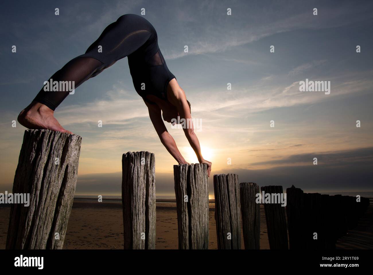 Donna sportiva che fa yoga in riva al mare Foto Stock