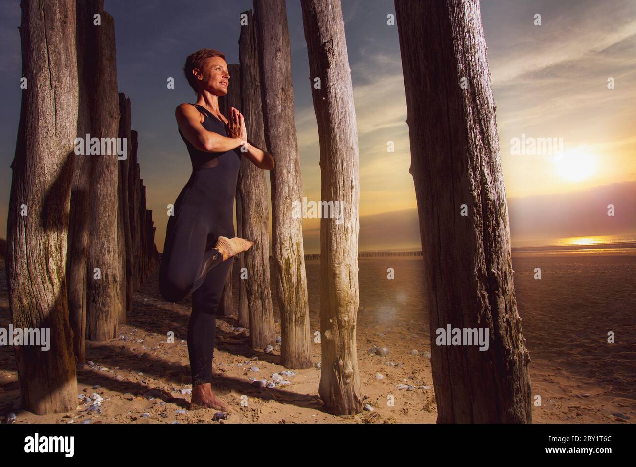 Donna sportiva che fa yoga in riva al mare Foto Stock