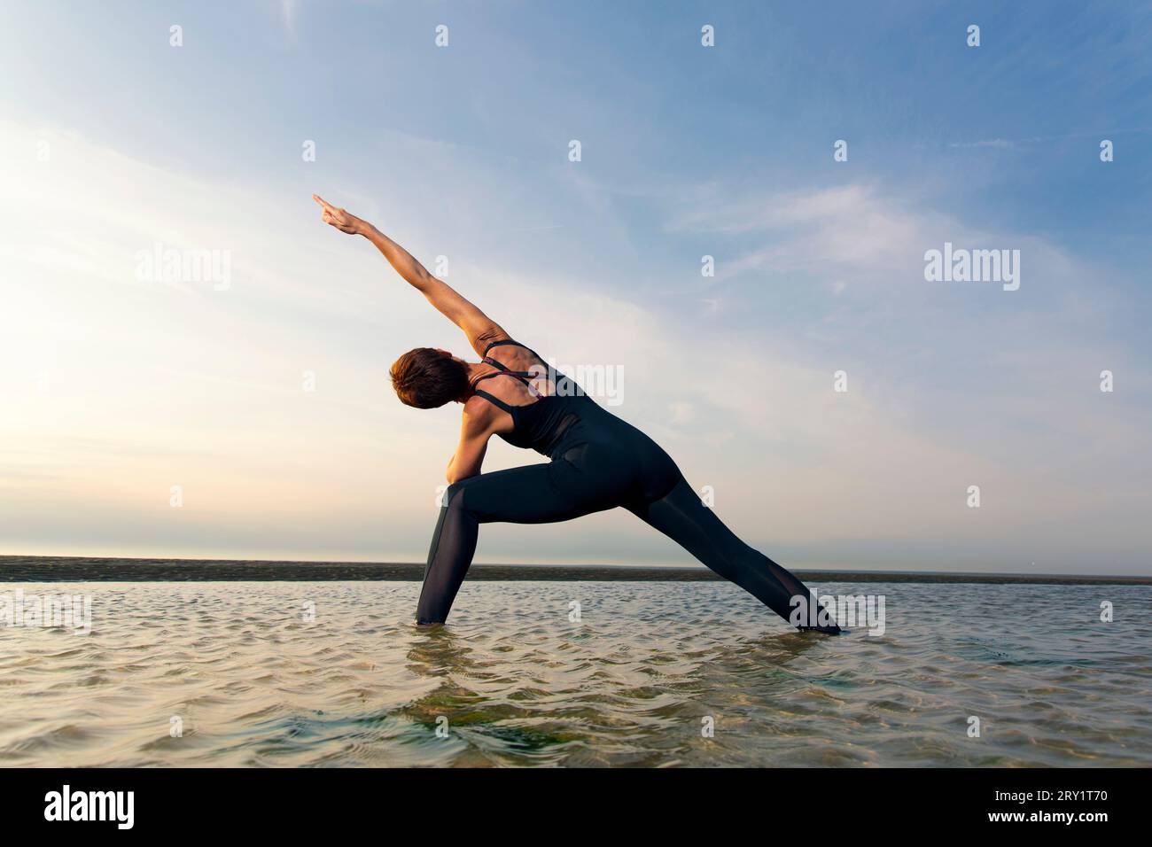 Donna sportiva che fa yoga in riva al mare Foto Stock