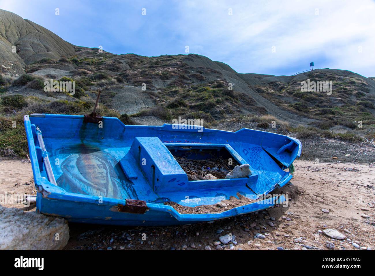 Europa, Italia, Sicilia, barca migrante abbandonata dipinta di blu su una spiaggia Foto Stock