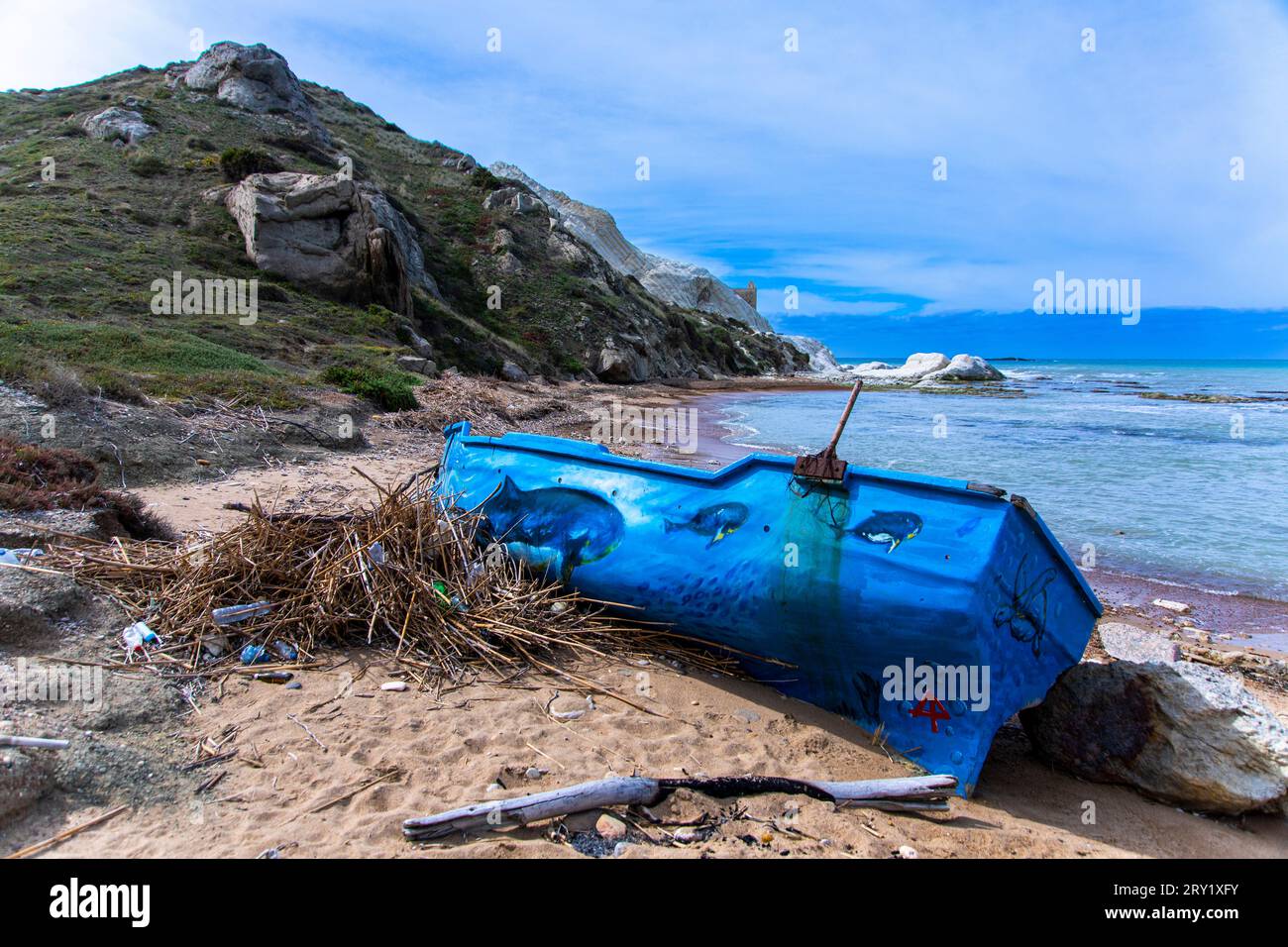 Europa, Italia, Sicilia, barca migrante abbandonata dipinta di blu su una spiaggia Foto Stock