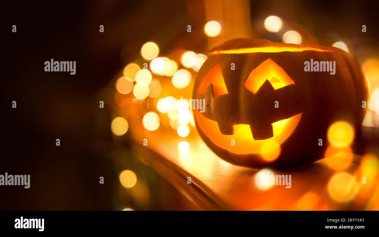 Un allegro Jack o Lanterna sorridente su halloween posto su un caminetto con le luci delle fate sullo sfondo Foto Stock
