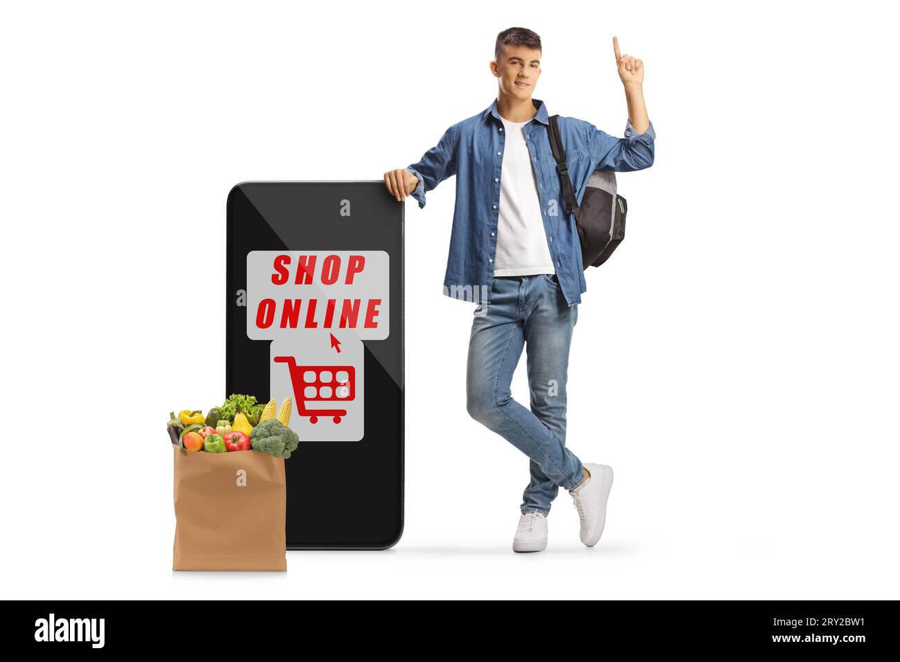 Studente maschio che punta verso l'alto e si appoggia su un telefono cellulare con l'app per lo shopping online e una borsa della spesa isolata su sfondo bianco Foto Stock