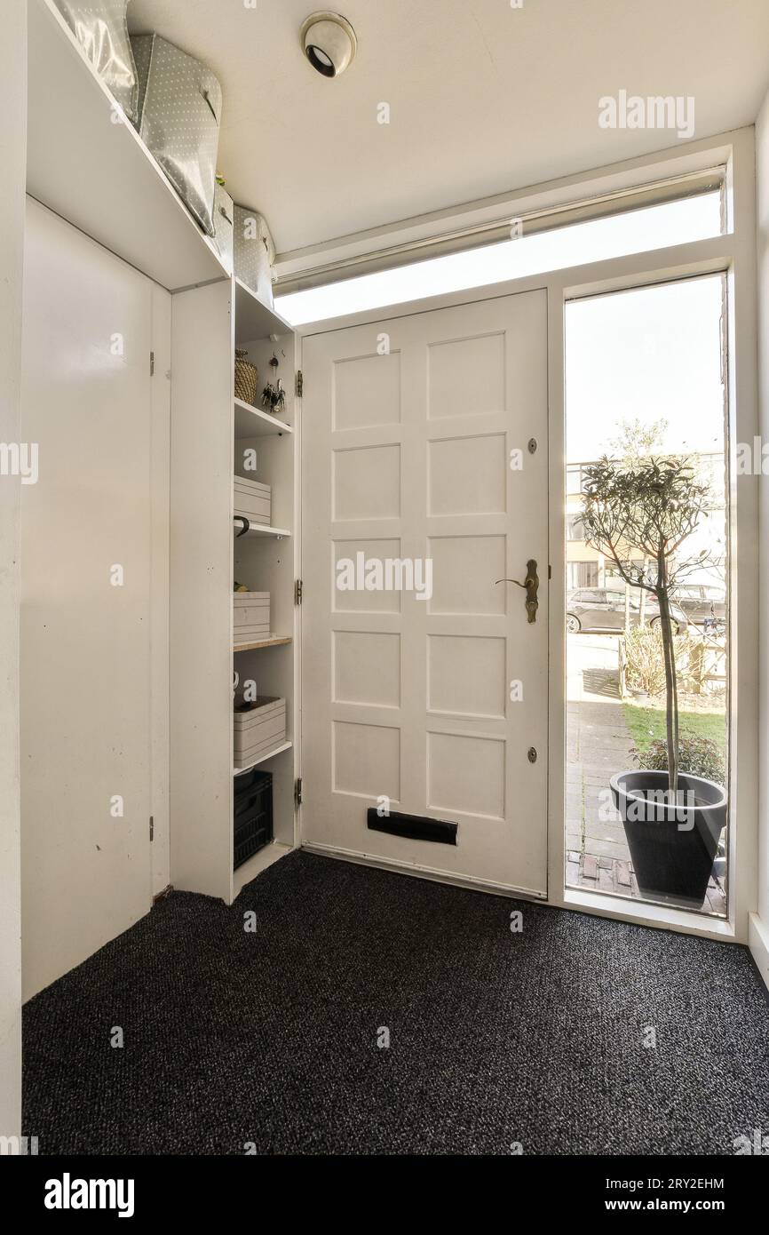 Ripiani bianchi con scatole situati accanto alla porta chiusa all'ingresso su una casa bianca chiara durante il giorno Foto Stock