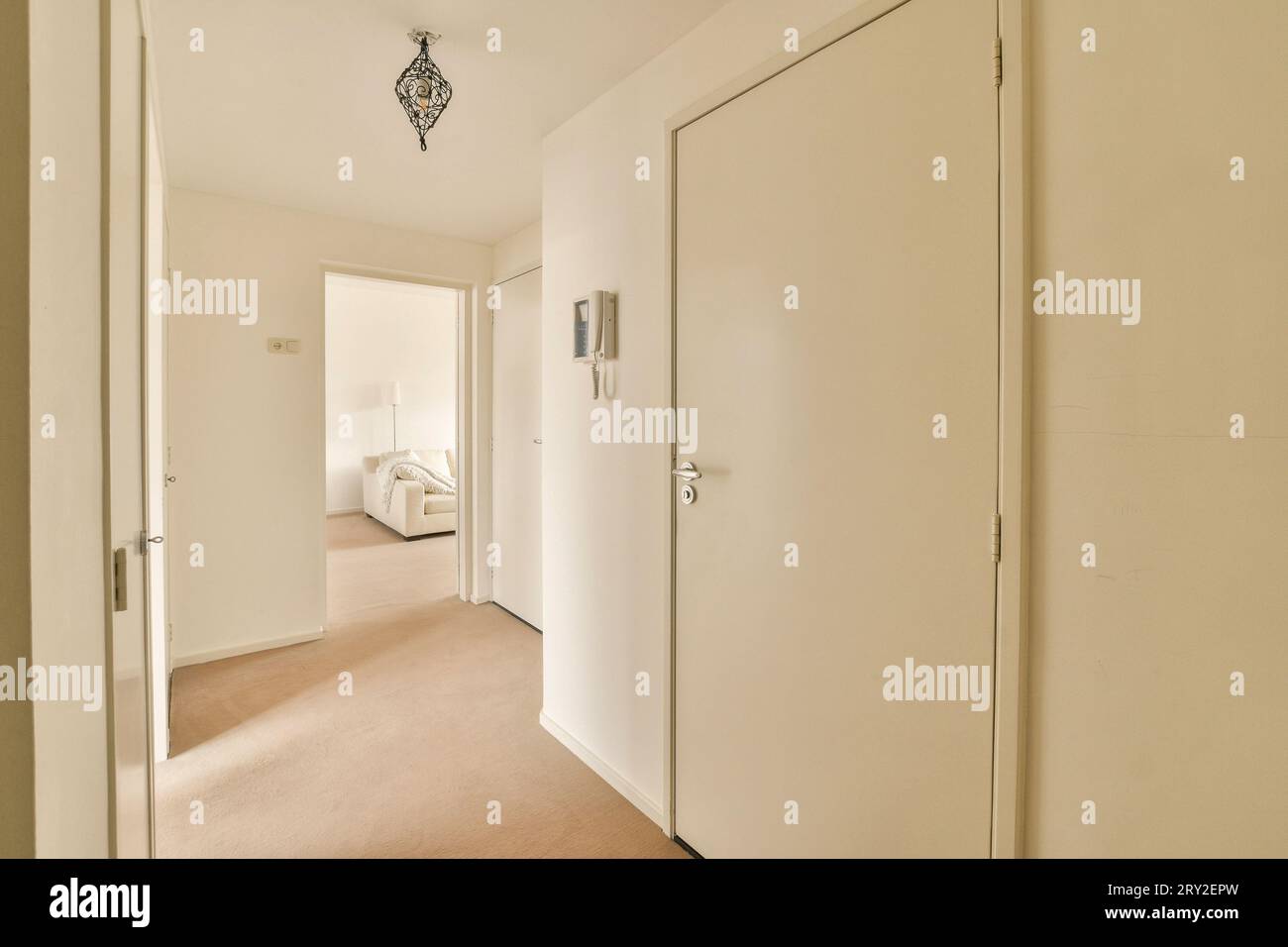 Interno di una stanza vuota e due porte e lampada appesa al soffitto in uno spazioso appartamento con pareti bianche Foto Stock