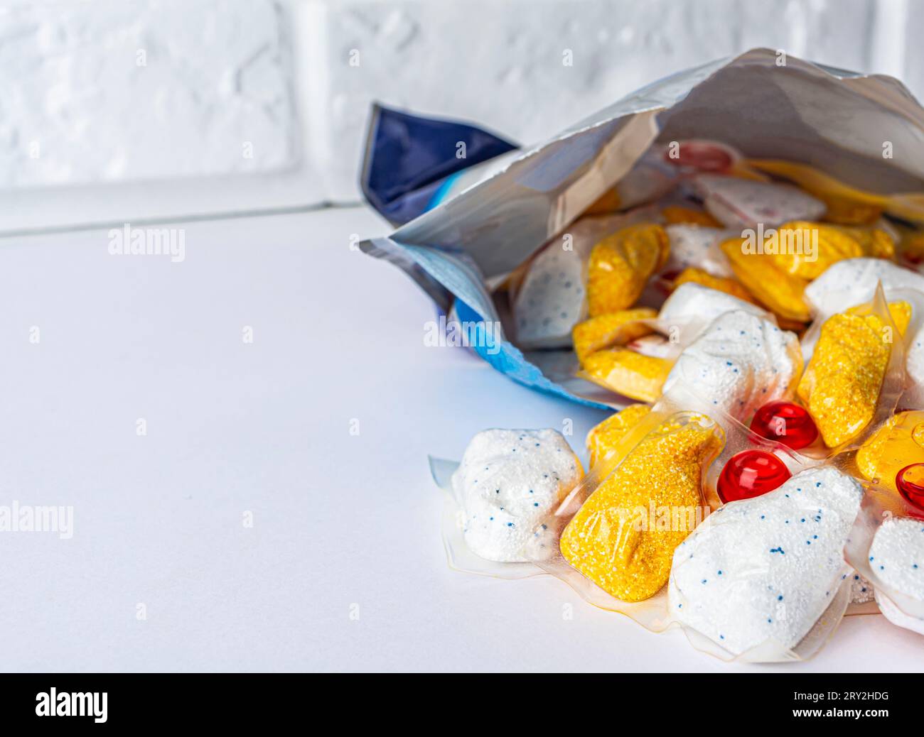 capsule per lavare i piatti davanti a una confezione aperta su sfondo bianco. Foto di alta qualità Foto Stock