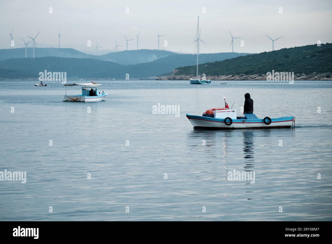 Barche da pesca sul mare con mulini a vento sul retro Foto Stock