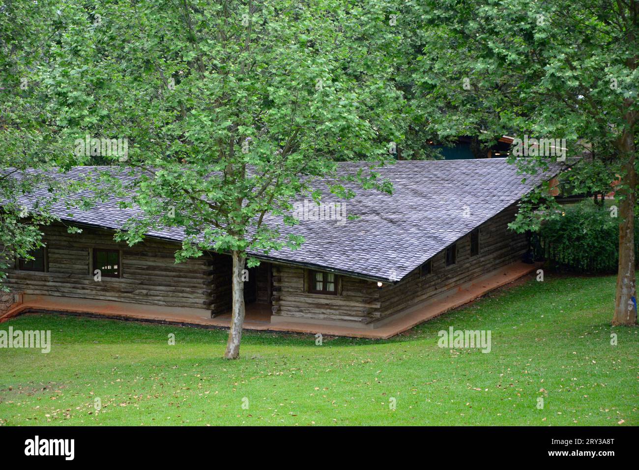 Casa in legno con tetto in lastra scura circondata da natura Foto Stock