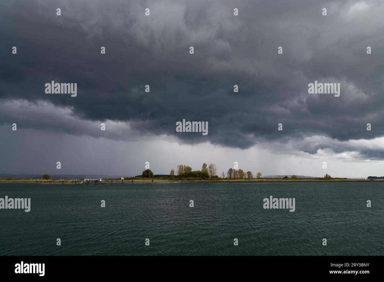 Le nuvole di tempesta attraversano Jetty Island in autunno mentre il vento strappa l'acqua Foto Stock