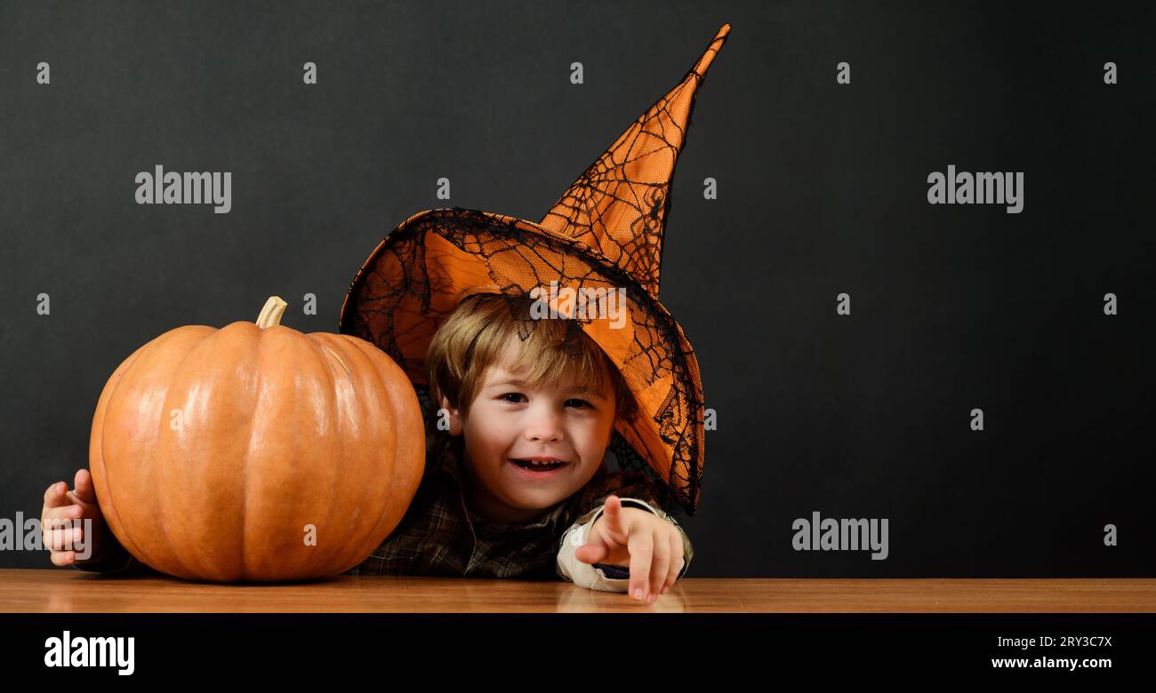 Halloween. Bambino sorridente in cappello da strega con zucca di Halloween. Piccolo mago, mago si prepara per le vacanze di Halloween. Piccolo ragazzo di Halloween con Foto Stock