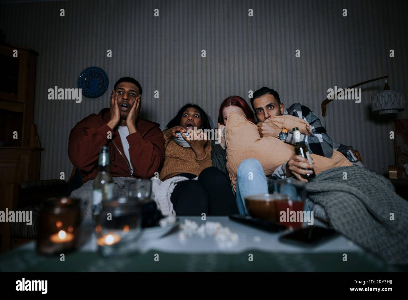 Amici multirazziali spaventati che guardano un film spaventoso in cabina Foto Stock