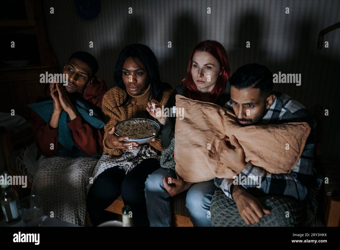 Amici multirazziali maschili e femminili che guardano un film spaventoso in cabina Foto Stock