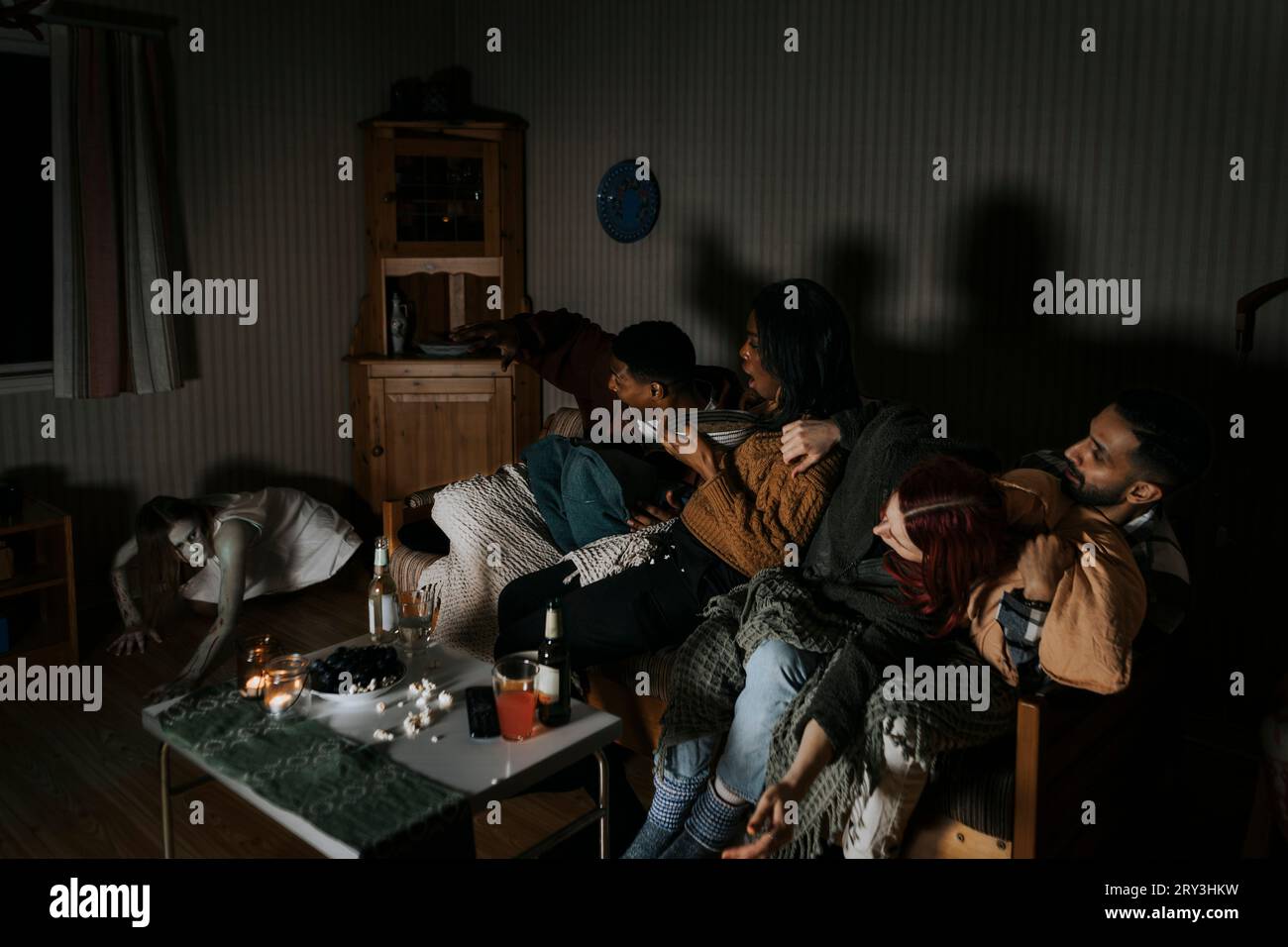 Spaventati amici multirazziali che guardano spettrali fantasmi mentre guardano spaventosi film in cabina Foto Stock