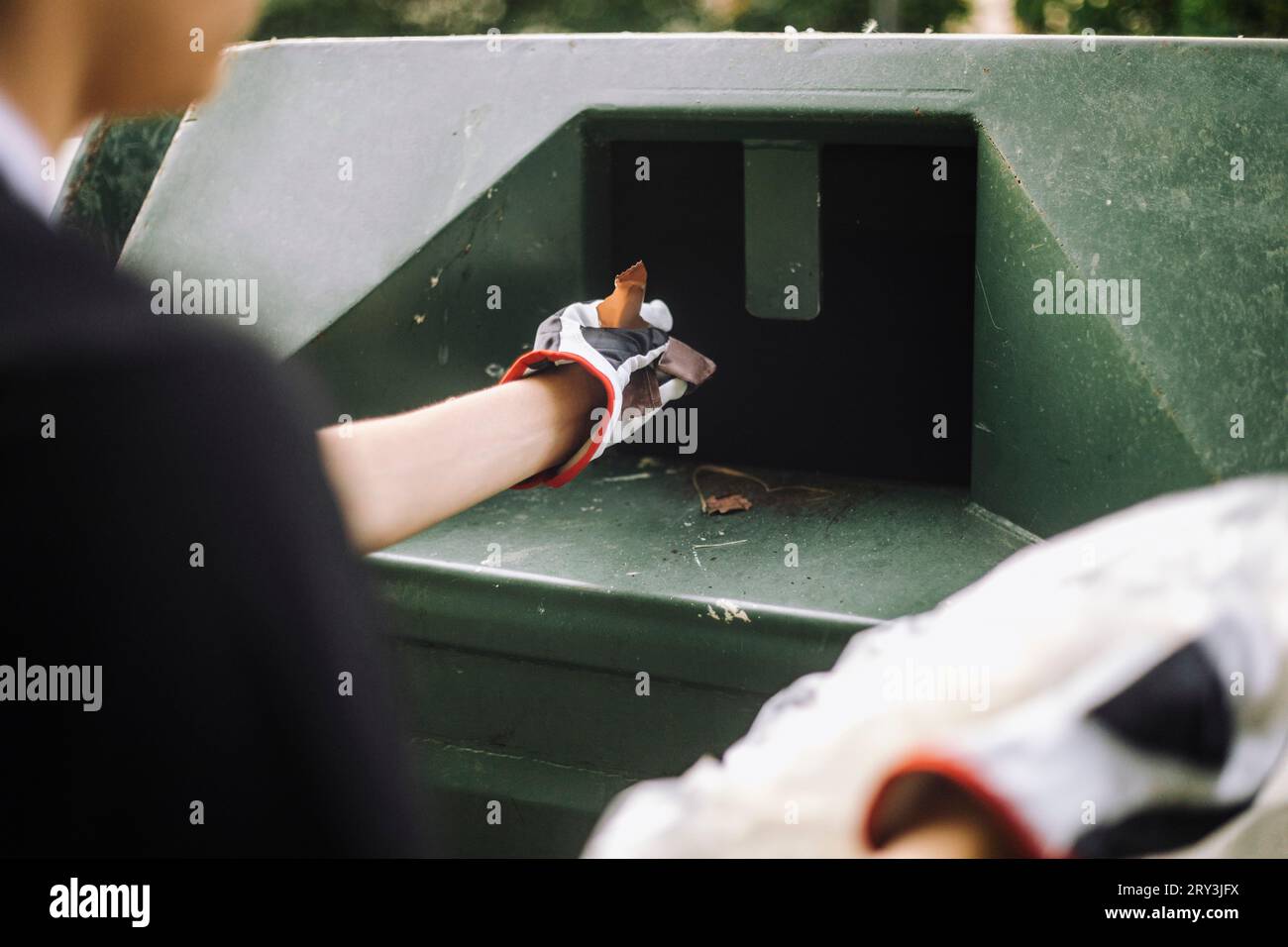 Sezione centrale del ragazzo adolescente che mette i rifiuti di plastica nel cestino Foto Stock