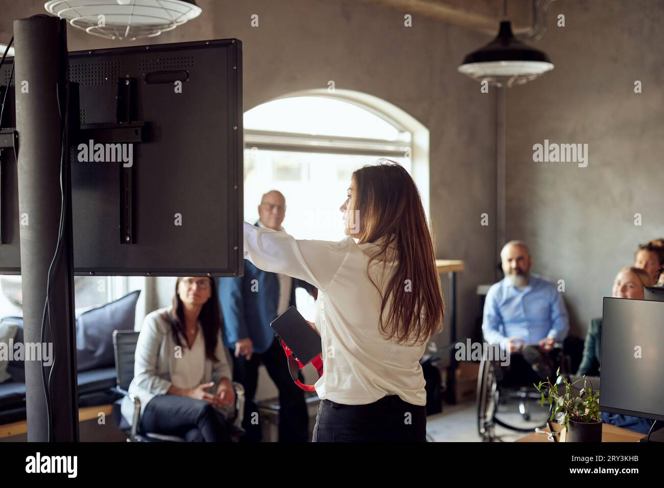 Donna d'affari che spiega ai colleghi durante una riunione in un ufficio creativo Foto Stock