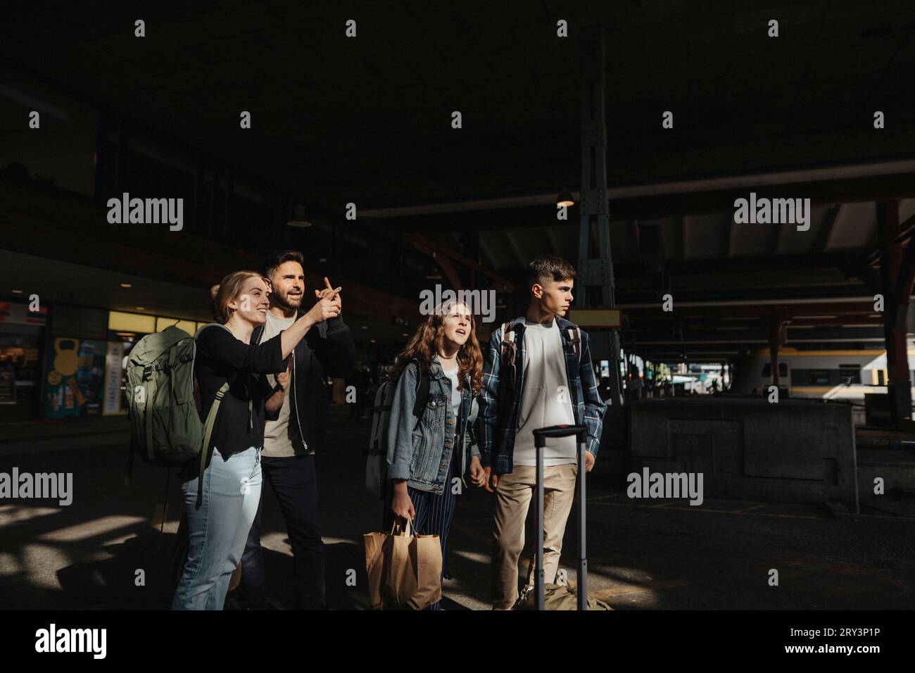 Famiglia che parla tra di loro mentre aspetta il treno alla stazione ferroviaria Foto Stock