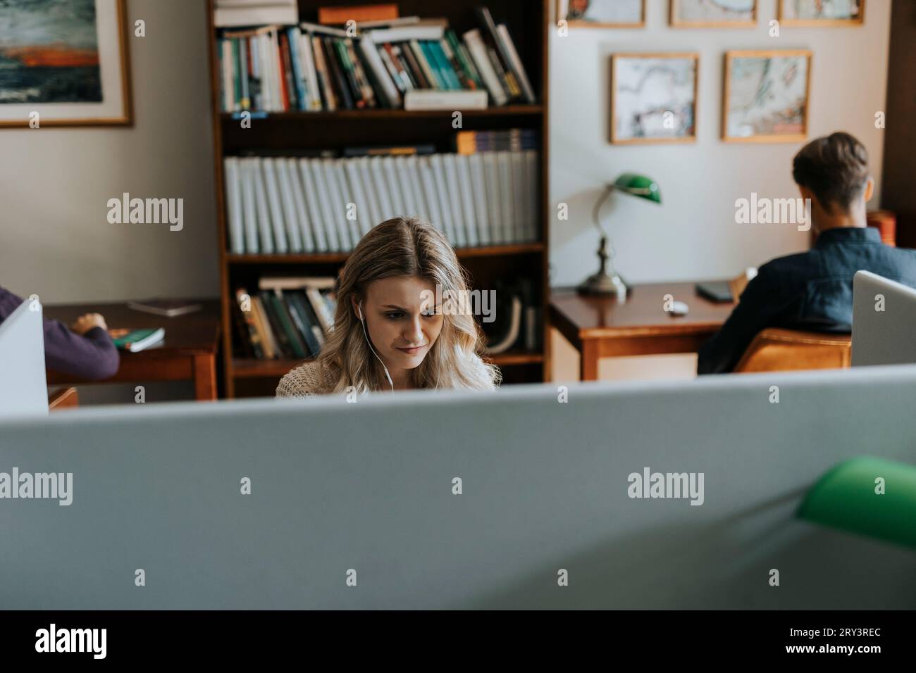 Giovane donna bionda seduta in biblioteca Foto Stock