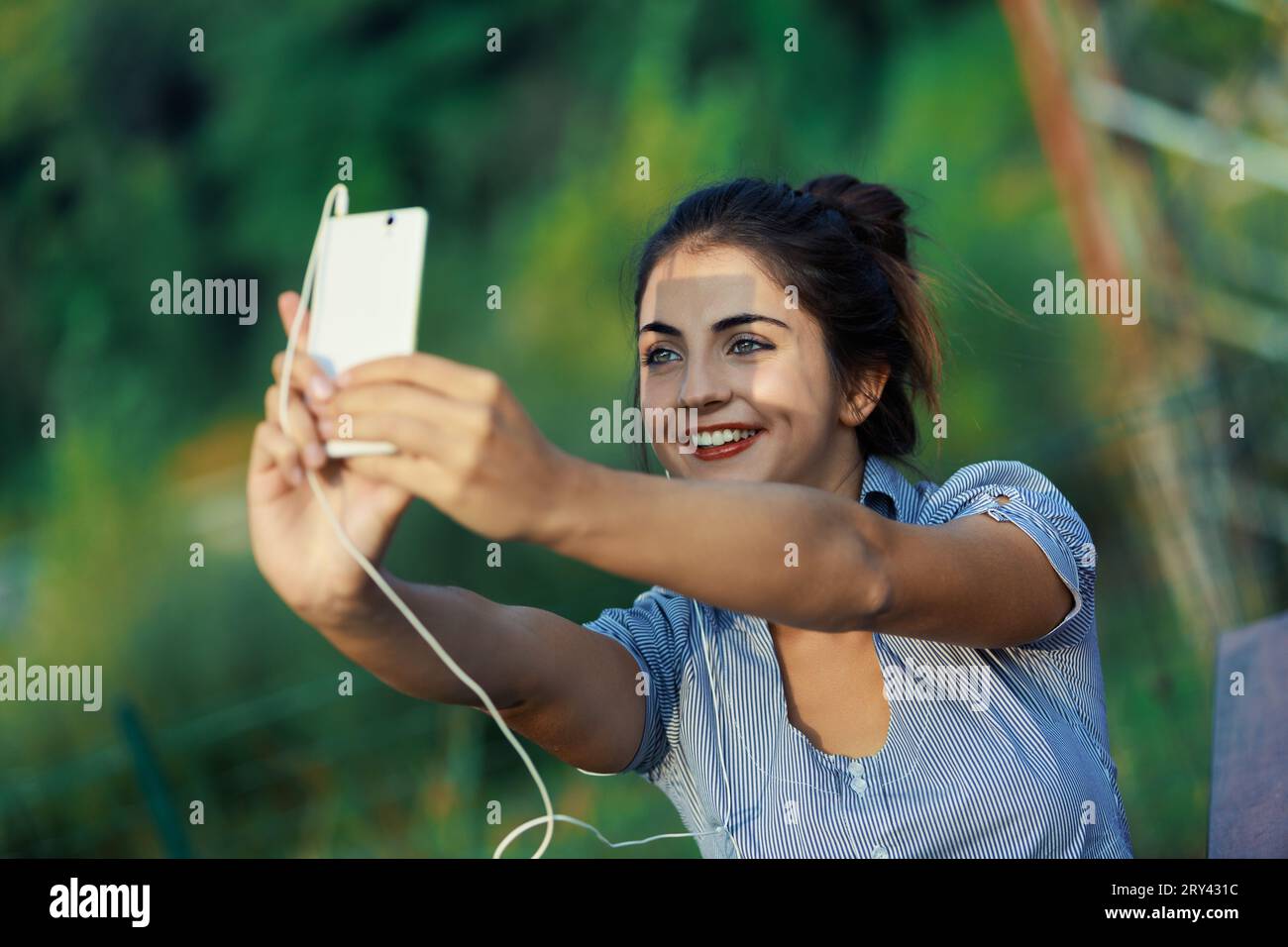 Utilizzando uno smartphone all'aperto per il divertimento e la crescita professionale, una giovane donna approfondisce l'influencer marketing, la creazione di contenuti e la produzione di video Foto Stock