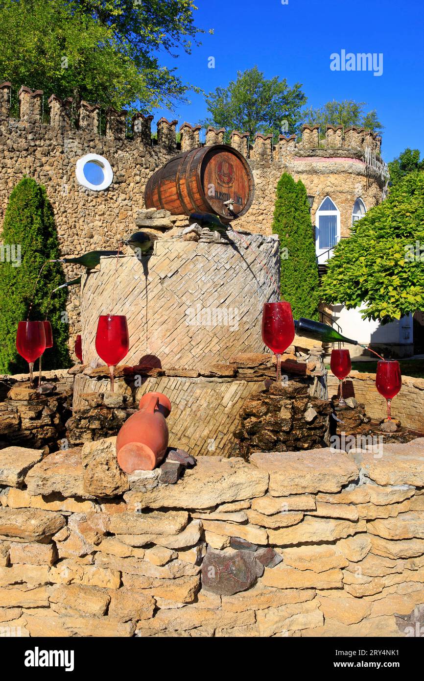 Bottiglie di vino che riversano il vino rosso nelle glassa di vino presso la fontana del vino dell'azienda vinicola Milestii Mici a Milestii Mici, Moldavia Foto Stock