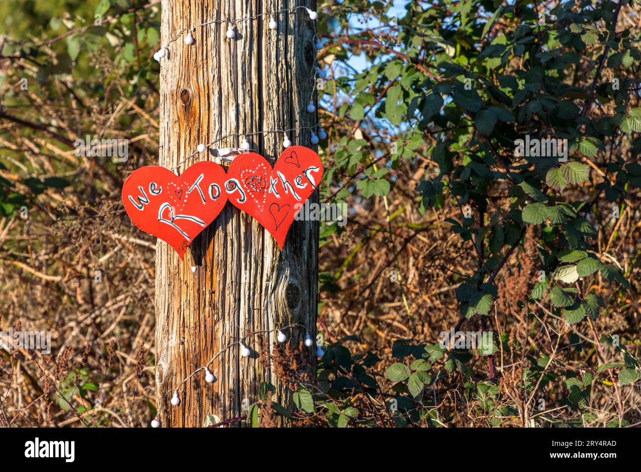 Due cuori rossi dipinti con le parole "We R Together" esposte su un palo di legno a Vancouver, Canada Foto Stock