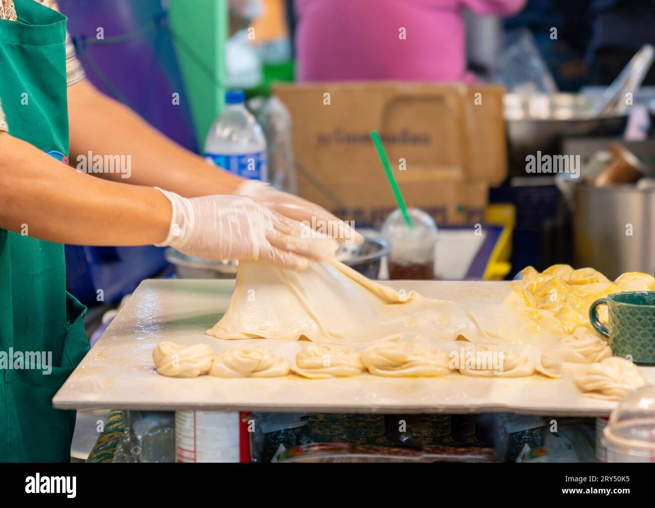 L'impasto Roti viene allungato e schiaffeggiato in un foglio prima di essere fritto in padella calda. Foto Stock