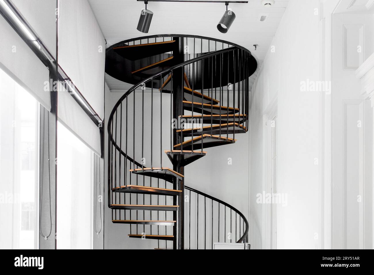 Scala a spirale, gradini moderni in legno e nero con interno bianco e illuminazione pista Foto Stock