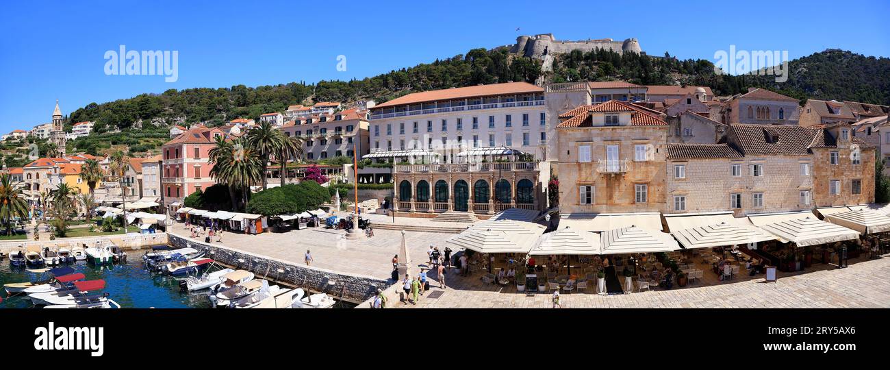 Vista panoramica di Hvar, tra cui la fortezza sulla collina e negozi, ristoranti e porto in primo piano, Croazia Foto Stock