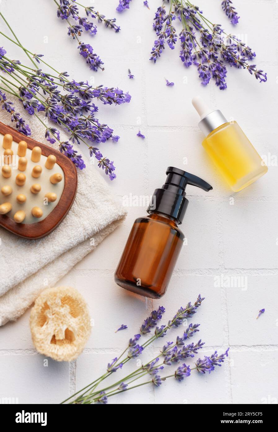 Vasca idromassaggio con lavanda. Sale di lavanda, olio essenziale naturale, spazzole per massaggi e lavanda fresca su fondo di piastrelle bianche. Foto Stock
