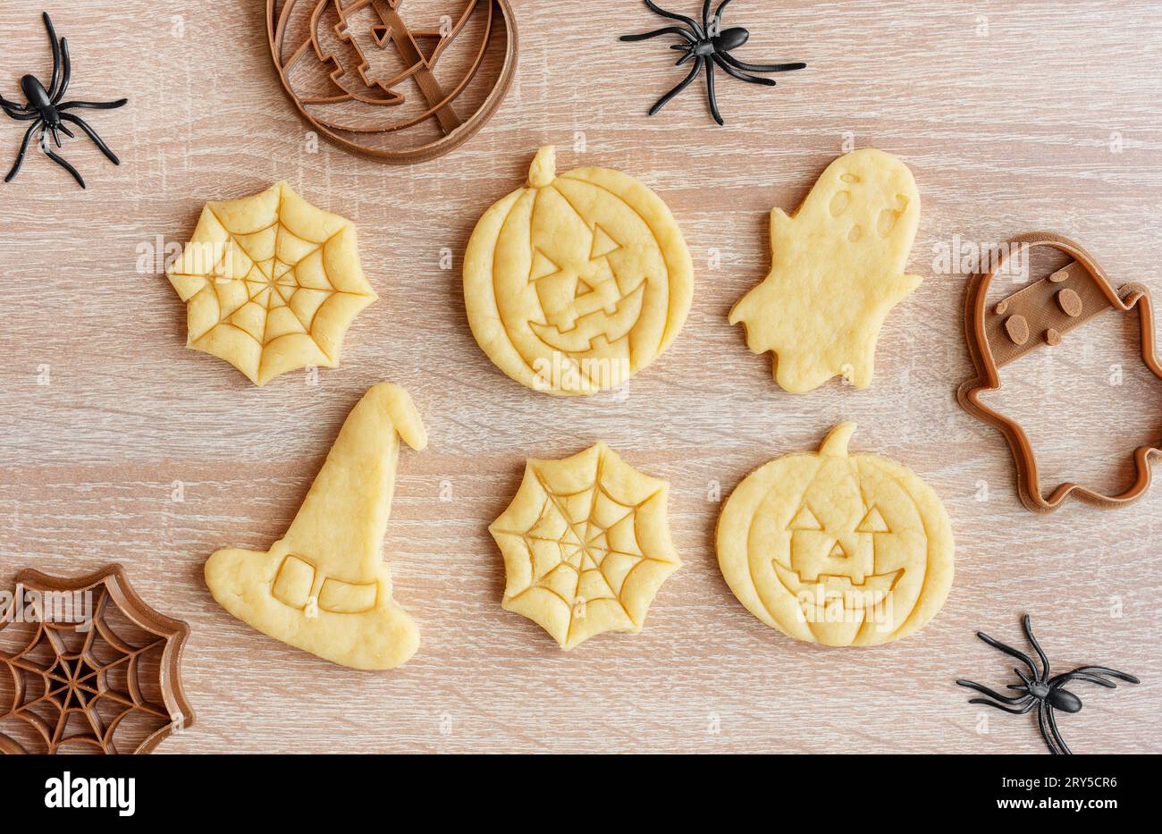 Preparazione di biscotti per le feste da cuocere in forno. Biscotti di Halloween pronti da cuocere a forma di zucche e fantasmi Foto Stock