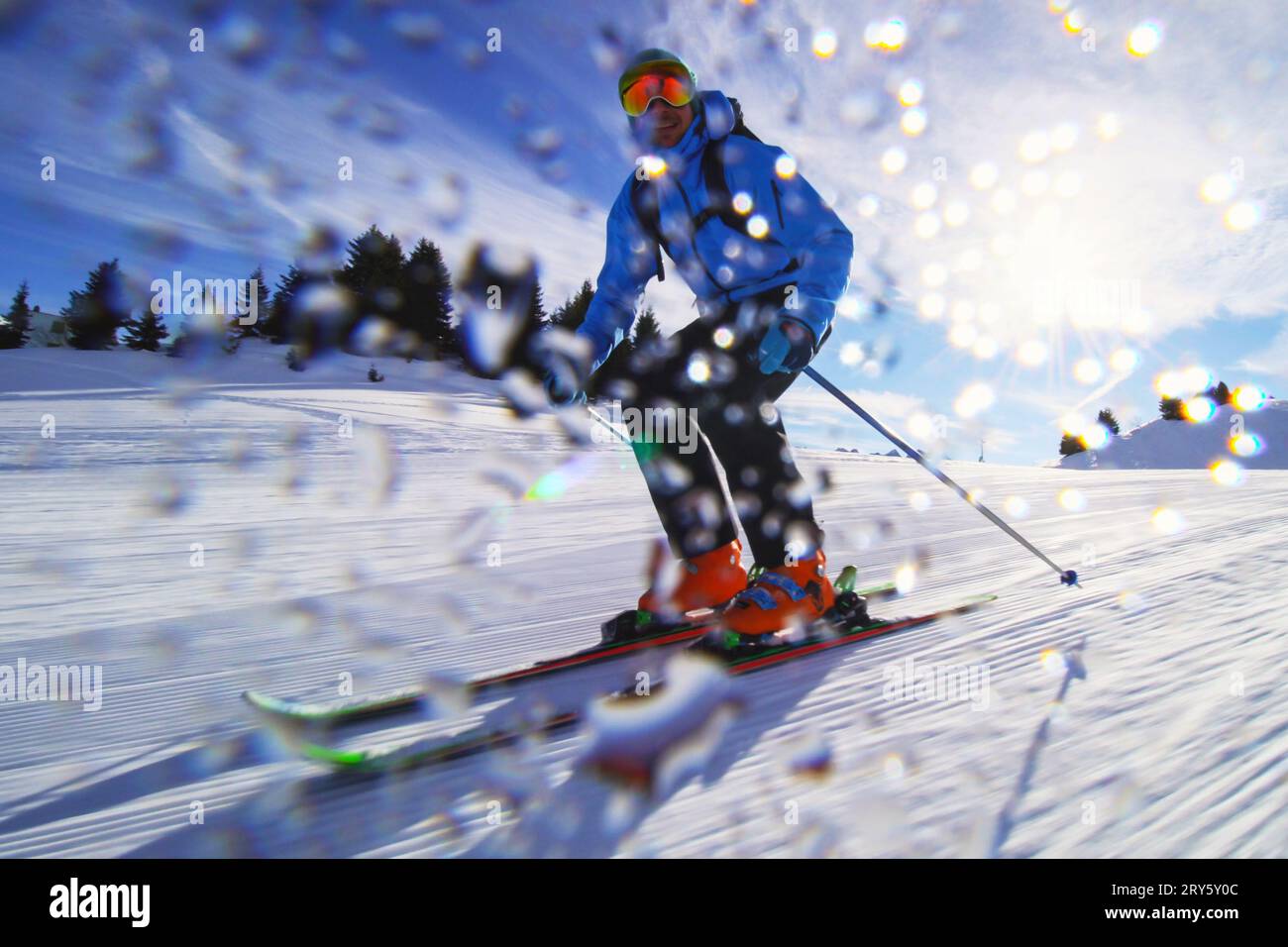 Sciatore professionista sulle piste delle alpi Svizzere e sciando la neve alla macchina fotografica. Gocce d'acqua visibili. Foto Stock