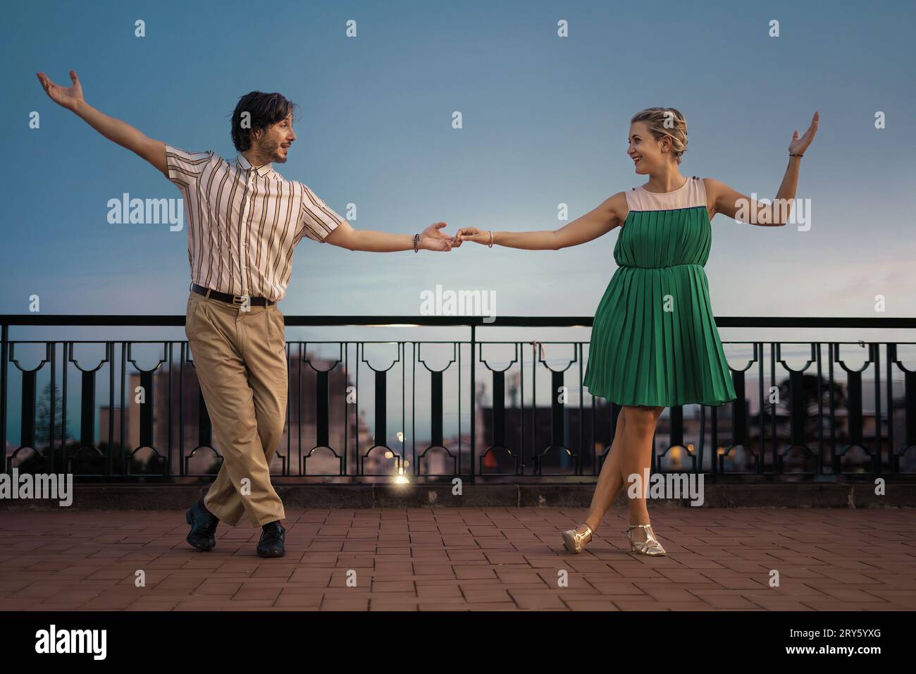 Dondola in coppia su una terrazza, catturata nel profilo mentre si tengono per mano. L'ampio sfondo offre ampio spazio per il testo. Foto Stock