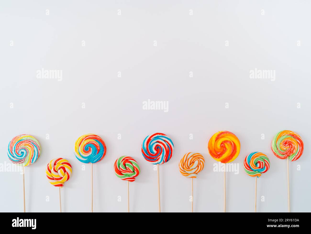 Lecca-lecca con colori vivaci su sfondo bianco. Concetto estivo. Composizione creativa di caramelle. Minima idea dolce. Spazio di copia per il testo. Foto Stock